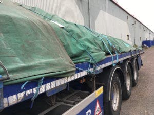 a heavy duty green tarp protecting construction supplies on a flatbed truck