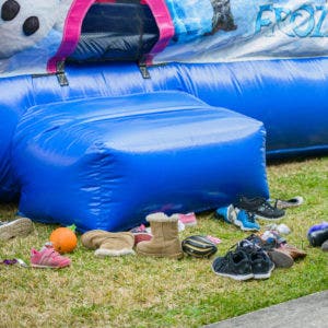 pairs of children's shoes stockpiled at the entrance way of a bounce house